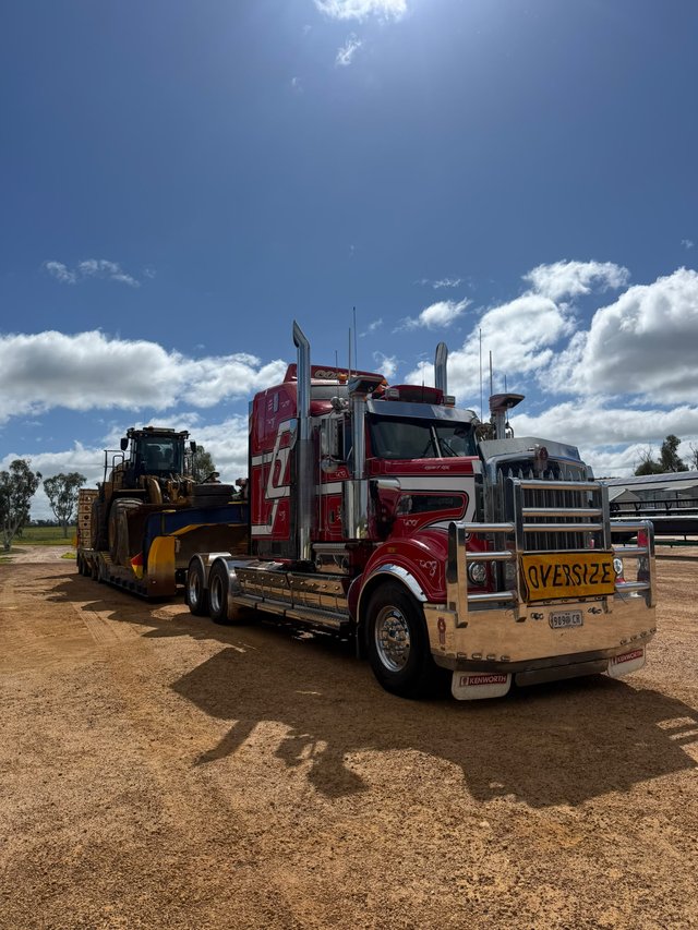 Kenworth T909 float truck transporting a loader for a customer